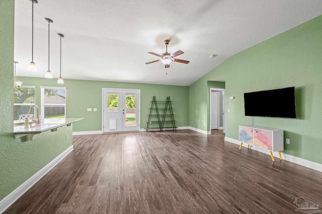 unfurnished living room featuring ceiling fan, vaulted ceiling, wood finished floors, a sink, and baseboards