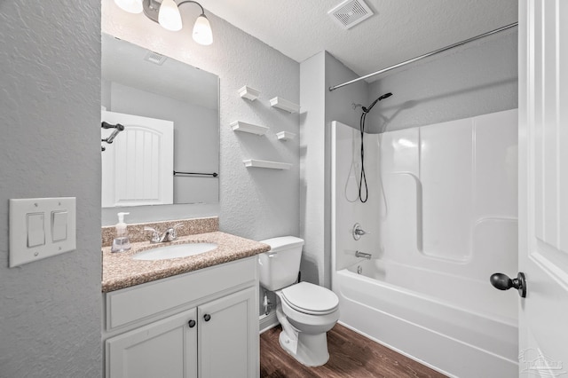full bathroom with a textured wall, vanity, a textured ceiling, wood finished floors, and visible vents