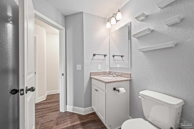 bathroom featuring vanity, a textured wall, wood finished floors, and toilet