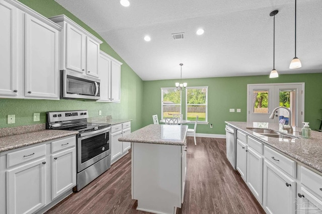 kitchen featuring dark wood-style flooring, a kitchen island, white cabinets, a sink, and stainless steel appliances