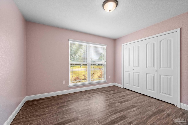 unfurnished bedroom featuring baseboards, dark wood finished floors, and a closet