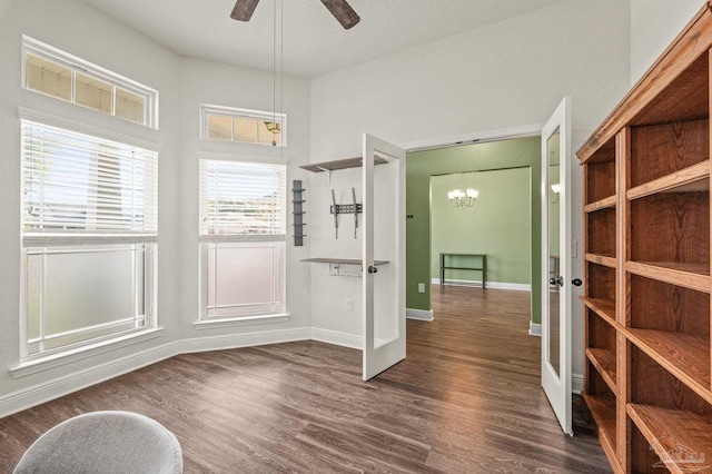 interior space featuring baseboards, dark wood-style floors, and ceiling fan with notable chandelier