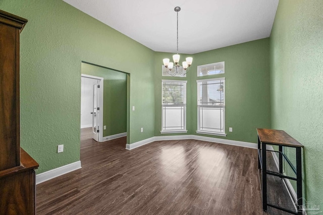 unfurnished dining area with baseboards, a textured wall, dark wood finished floors, and a notable chandelier