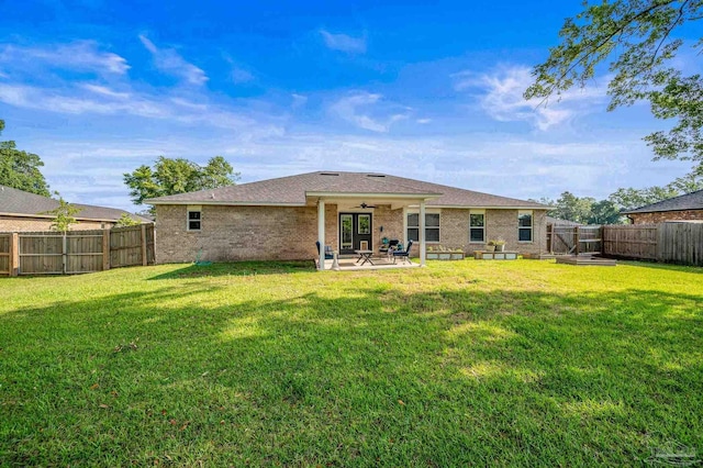 back of property with brick siding, ceiling fan, a fenced backyard, a patio, and a yard