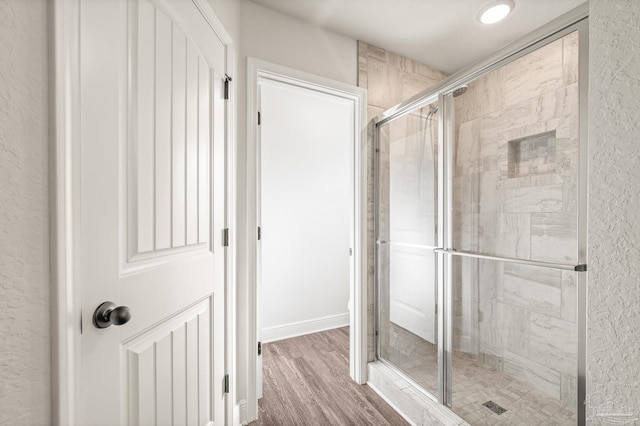 full bath featuring a stall shower and wood finished floors