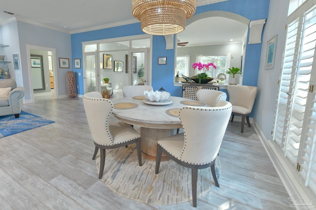 dining area with light hardwood / wood-style flooring, crown molding, and a chandelier