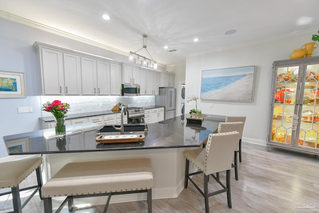 kitchen with stainless steel appliances, white cabinetry, pendant lighting, and a kitchen breakfast bar