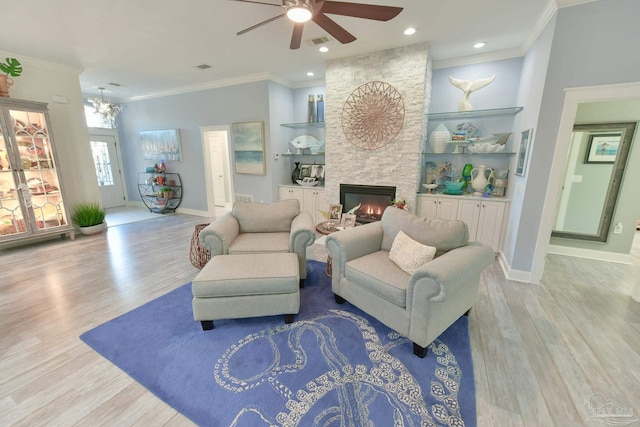 living room featuring a stone fireplace, built in features, light hardwood / wood-style floors, and ornamental molding