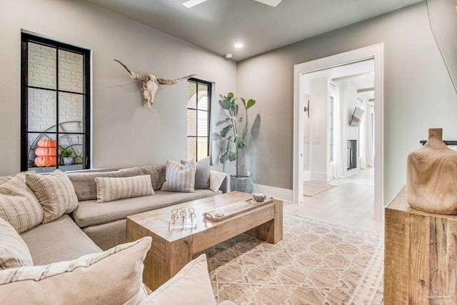 living room featuring a fireplace, ceiling fan, and light hardwood / wood-style flooring