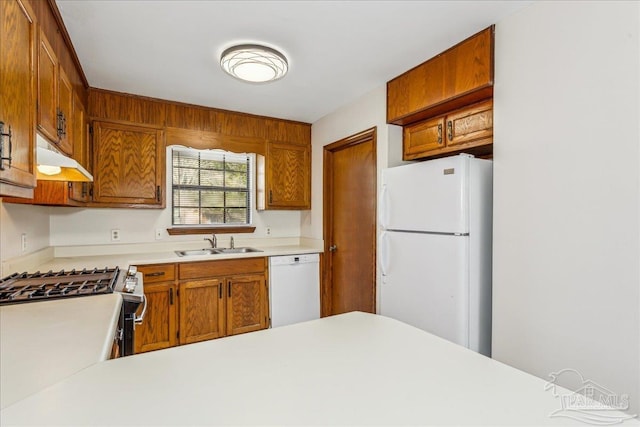 kitchen with white appliances, kitchen peninsula, and sink