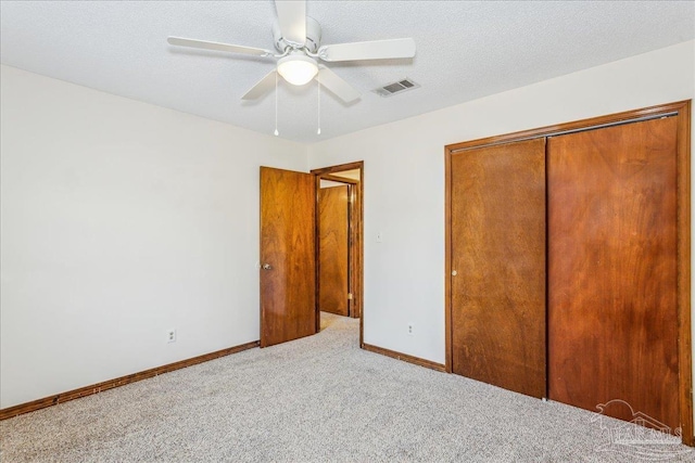 unfurnished bedroom featuring ceiling fan, light carpet, a textured ceiling, and a closet