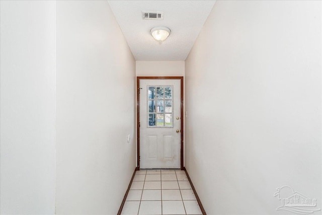 doorway featuring a textured ceiling and light tile patterned floors