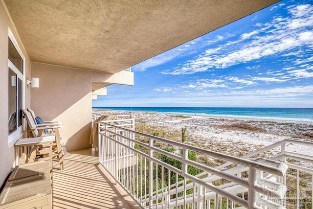 balcony featuring a view of the beach and a water view