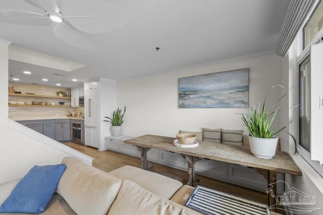 living room featuring ceiling fan, ornamental molding, and light hardwood / wood-style floors