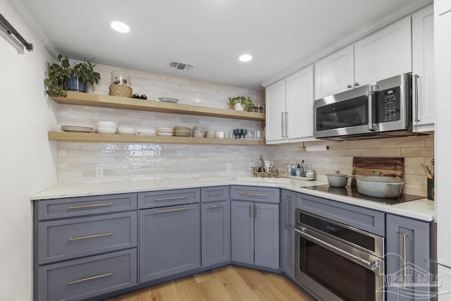 kitchen with white cabinets, backsplash, stainless steel appliances, and light hardwood / wood-style flooring