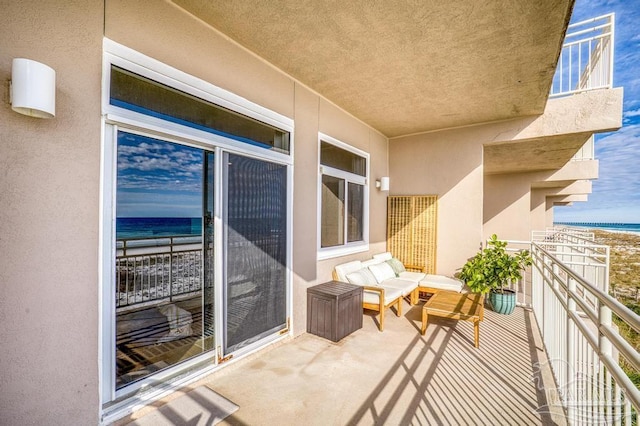 balcony with a view of the beach, a water view, and outdoor lounge area