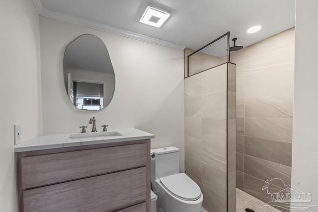 bathroom featuring toilet, crown molding, a tile shower, and vanity