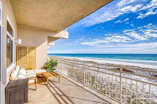 balcony with a water view, an outdoor hangout area, and a beach view