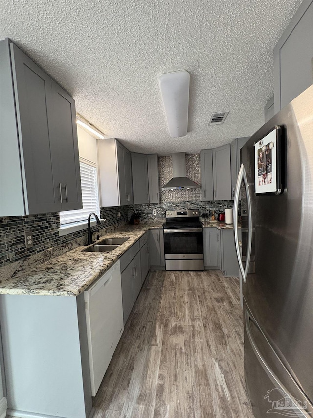 2654 Tinosa Cir, Pensacola, FL 32526 - kitchen featuring stainless steel appliances, gray cabinets, wall chimney exhaust hood, decorative backsplash, and a textured ceiling