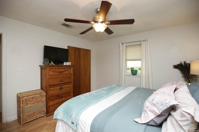 bedroom featuring ceiling fan, a closet, light hardwood / wood-style floors, and a textured ceiling