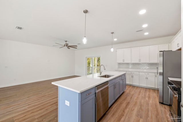 kitchen featuring stainless steel appliances, a sink, white cabinets, light countertops, and tasteful backsplash