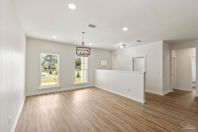 empty room with light wood-style floors, recessed lighting, visible vents, and baseboards