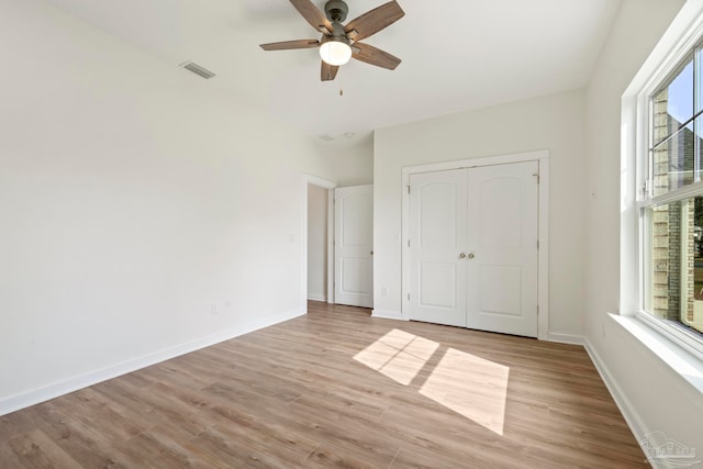 unfurnished bedroom with a closet, visible vents, light wood finished floors, and baseboards