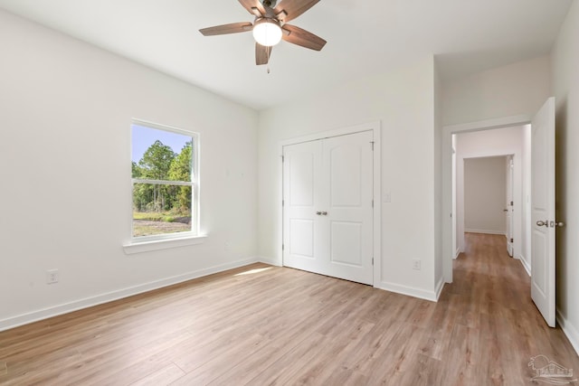 unfurnished bedroom with a ceiling fan, a closet, light wood-style flooring, and baseboards