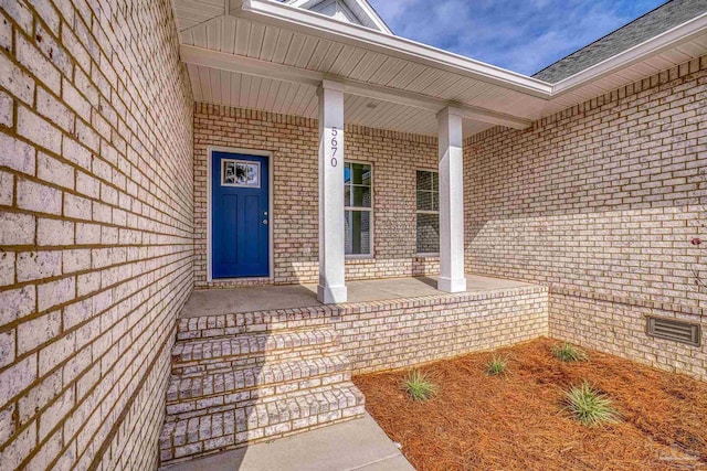 doorway to property with a porch, crawl space, and brick siding