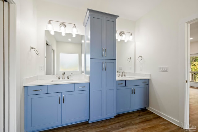 full bathroom featuring double vanity, a sink, baseboards, and wood finished floors