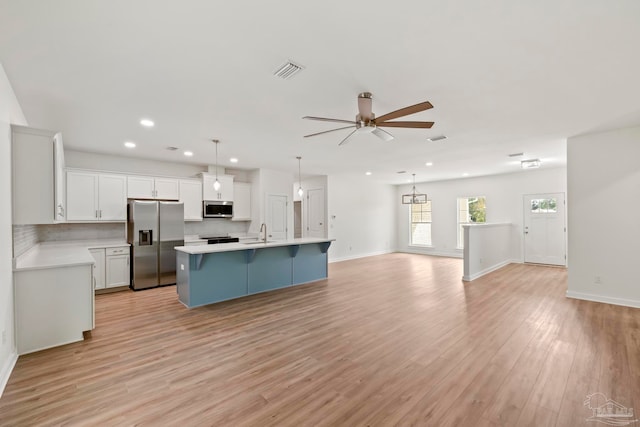 kitchen with a sink, visible vents, open floor plan, light countertops, and appliances with stainless steel finishes