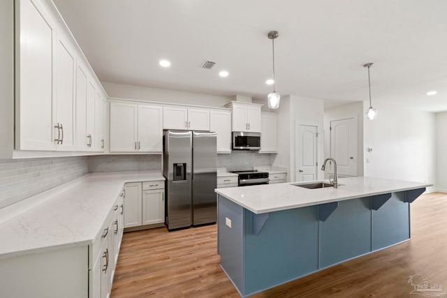 kitchen featuring appliances with stainless steel finishes, light wood-type flooring, a sink, and visible vents