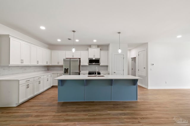 kitchen featuring white cabinets, light wood-style flooring, stainless steel appliances, and a sink