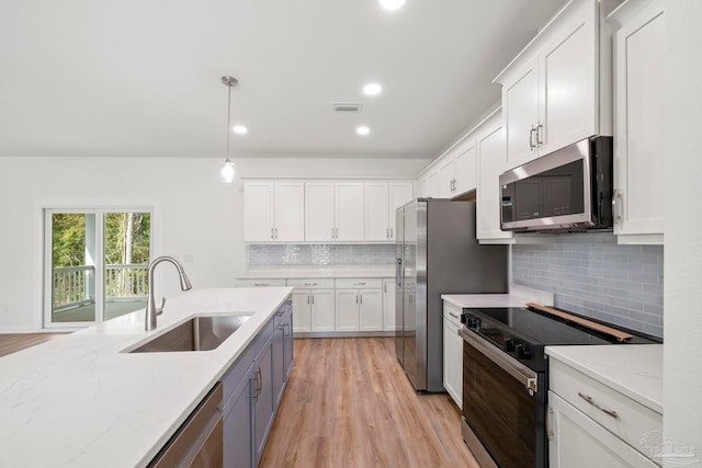 kitchen featuring stainless steel appliances, white cabinets, a sink, and visible vents