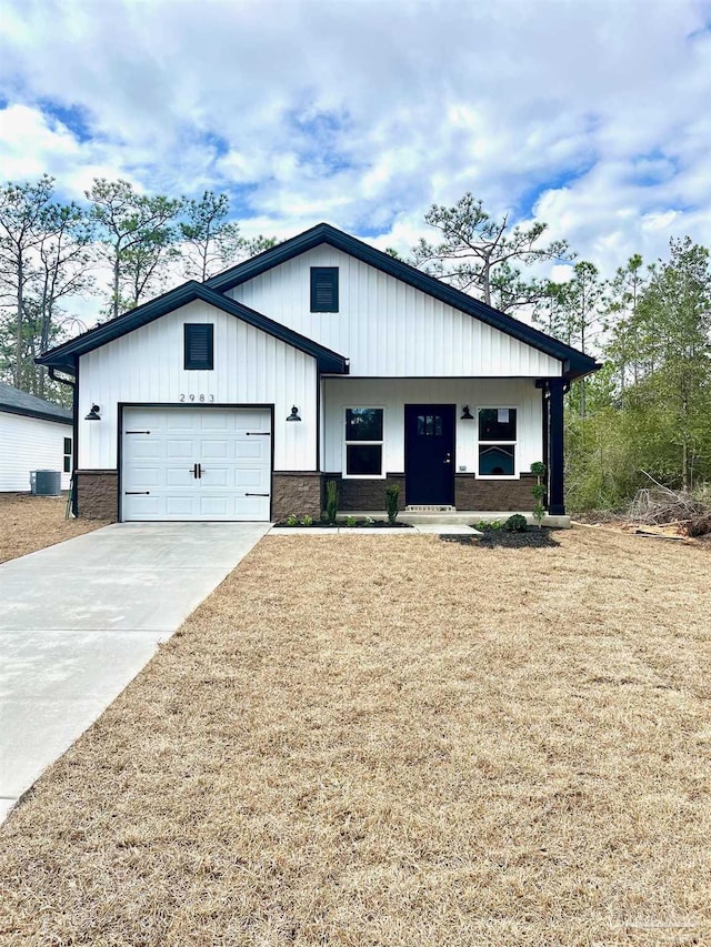 modern farmhouse featuring a garage, a porch, a front yard, and central air condition unit