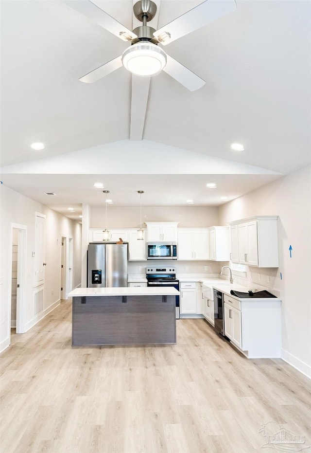 kitchen with appliances with stainless steel finishes, a center island, light countertops, and white cabinetry