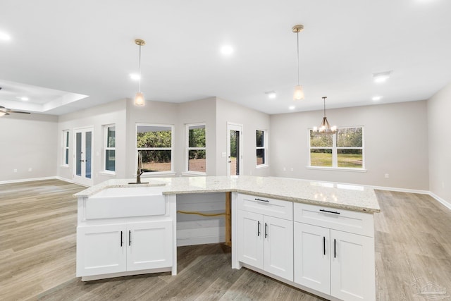 kitchen featuring light hardwood / wood-style flooring, sink, hanging light fixtures, and white cabinets