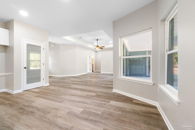 spare room featuring a raised ceiling, light hardwood / wood-style floors, and ceiling fan