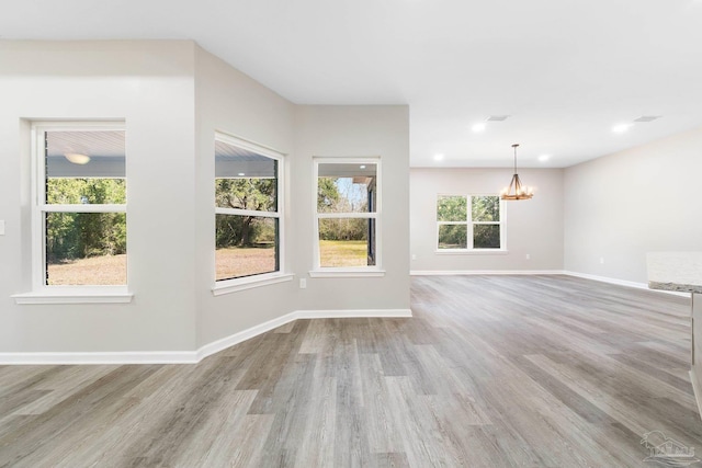 unfurnished room featuring light hardwood / wood-style floors and a notable chandelier