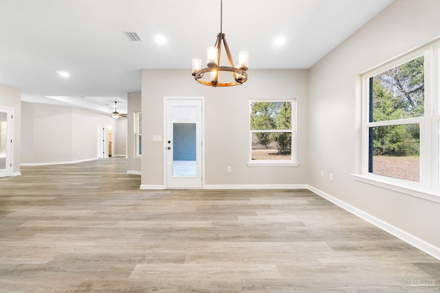 unfurnished room with ceiling fan with notable chandelier and light hardwood / wood-style floors