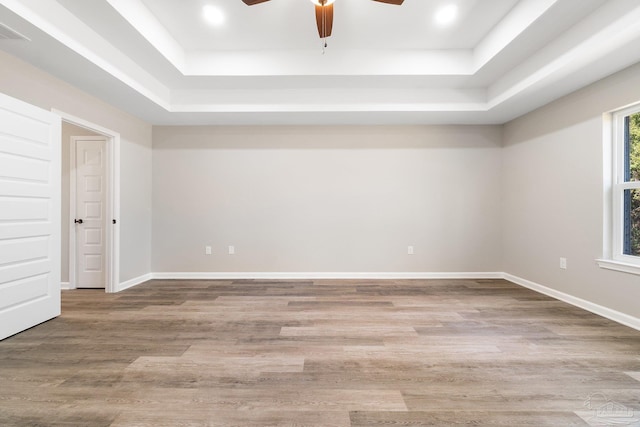 spare room featuring wood-type flooring, ceiling fan, and a tray ceiling