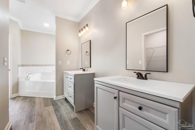 bathroom featuring hardwood / wood-style flooring, ornamental molding, vanity, and a tub