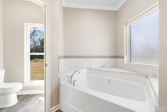 bathroom featuring a washtub, toilet, plenty of natural light, and ornamental molding