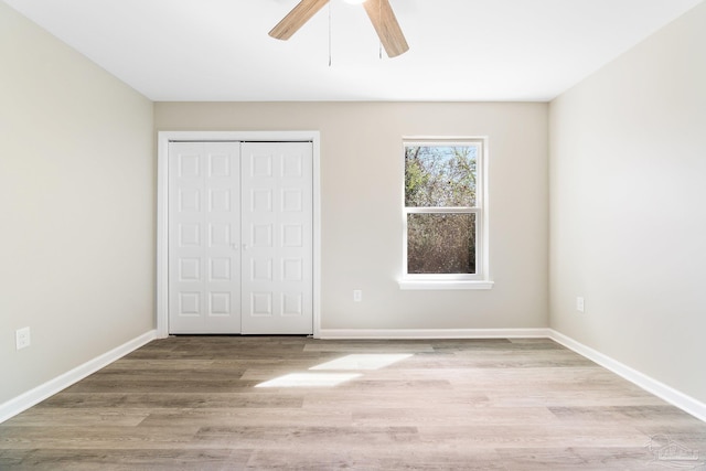 unfurnished bedroom with ceiling fan, light hardwood / wood-style flooring, and a closet