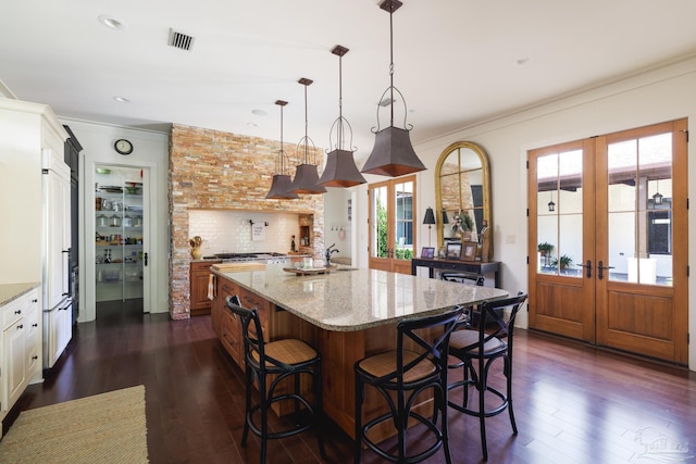 9 N Sunset Blvd, Gulf Breeze, FL 32561 - kitchen with french doors, ornamental molding, dark wood-style flooring, light stone counters, and decorative light fixtures