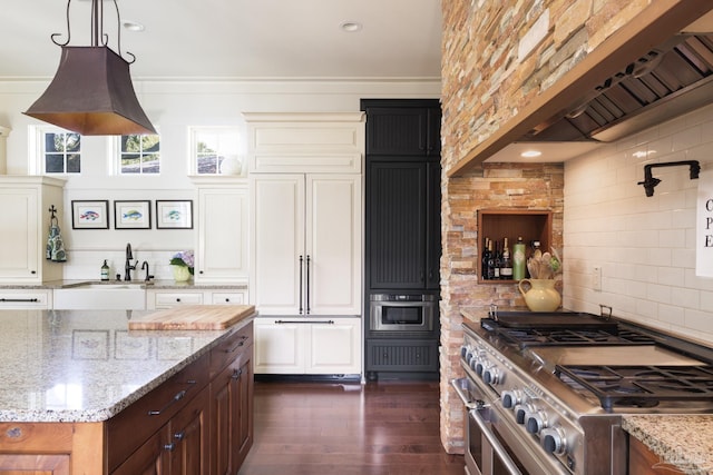 9 N Sunset Blvd, Gulf Breeze, FL 32561 - kitchen with high quality appliances, custom range hood, tasteful backsplash, dark wood-style floors, and white cabinets