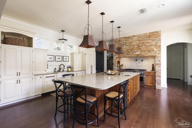 9 N Sunset Blvd, Gulf Breeze, FL 32561 - kitchen featuring high end stove, arched walkways, backsplash, light stone counters, and dark wood finished floors