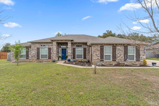 view of front of home with a front yard, fence, brick siding, and roof with shingles