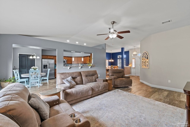 living area featuring visible vents, baseboards, recessed lighting, ceiling fan with notable chandelier, and light wood-style floors