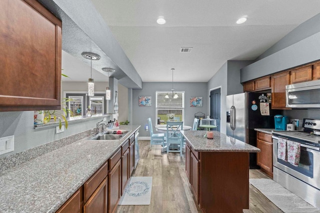 kitchen featuring a sink, stainless steel appliances, light wood-style floors, and pendant lighting